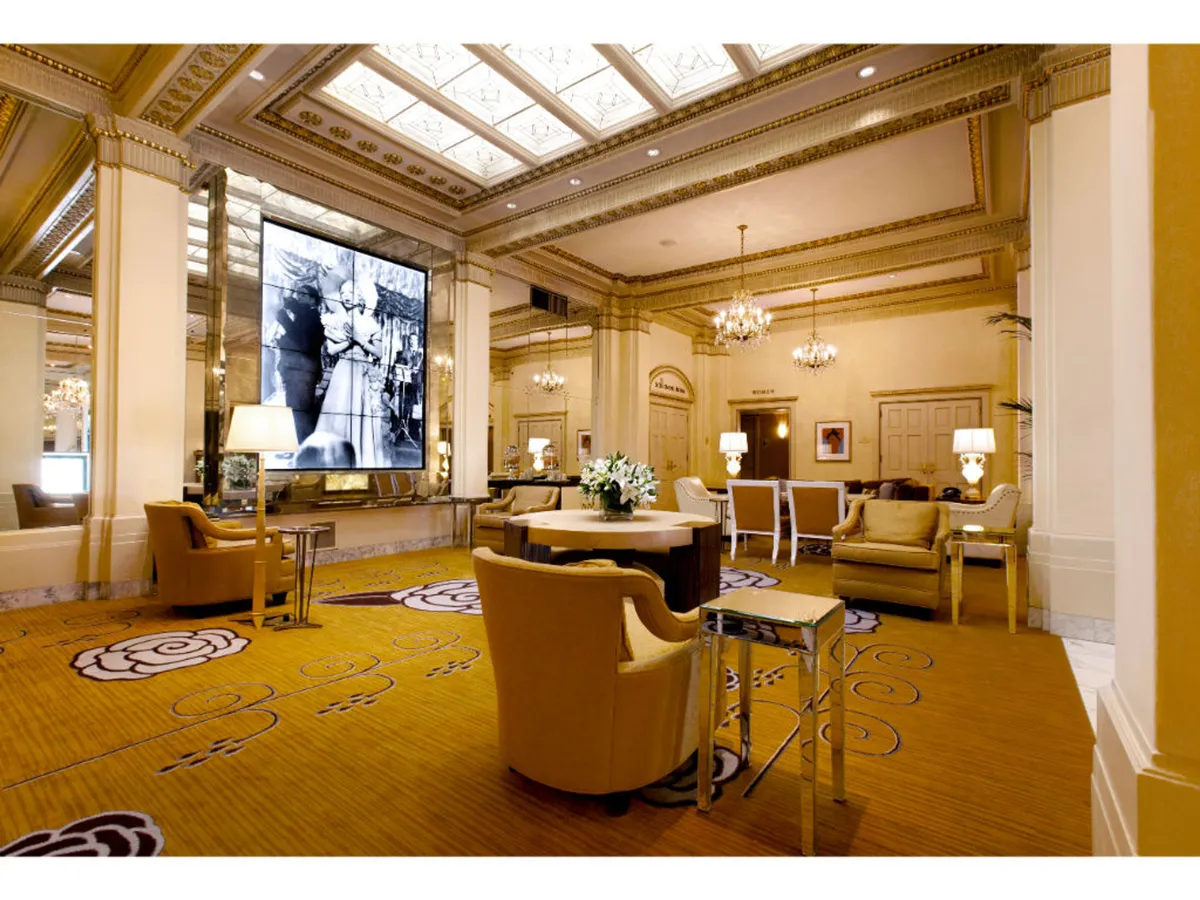 A screening room with a large screen displaying a black-and-white photo, a sparkling ornate chandelier, and stylish, comfortable seating arranged for group gatherings. The surrounding decor and floral centerpiece add to the sense of luxury and artistic immersion.