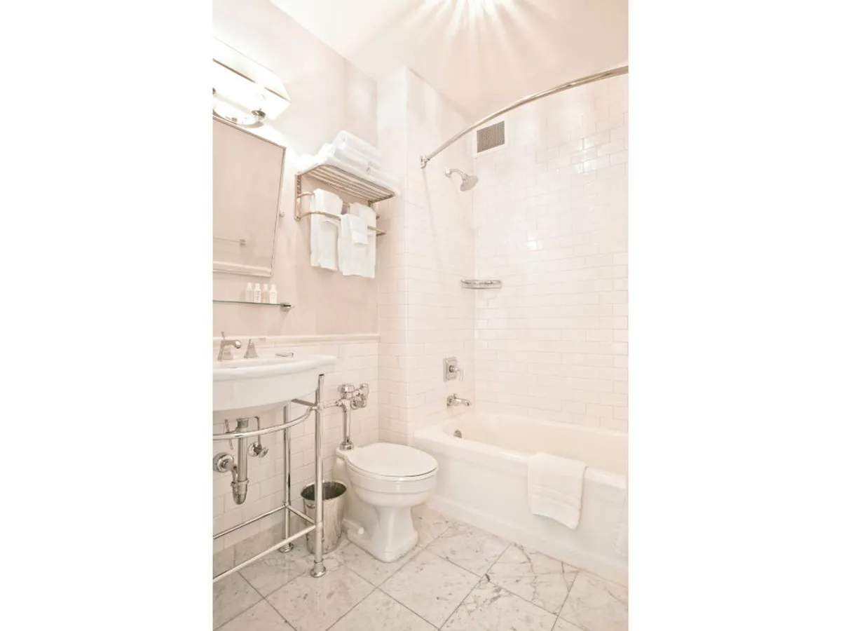 A serene bathroom with a sleek sink, a spacious bathtub/shower combo, and neatly arranged towels. The space is bright and inviting, designed for relaxation and personal care.